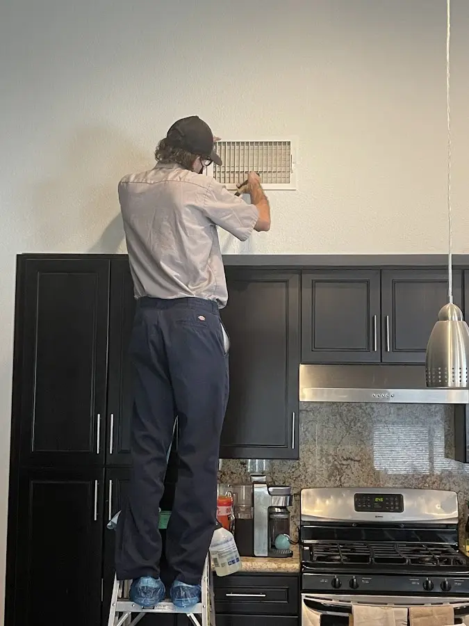 Technician inspecting an air vent during HVAC service in San Buenaventura (Ventura)